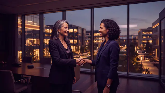 Illustration of two female technology leaders shaking hands in an office setting