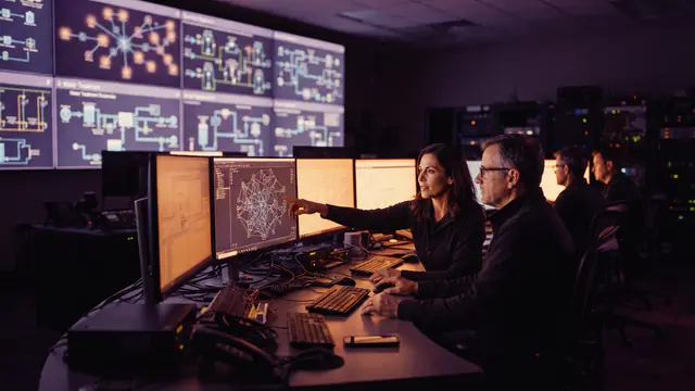 An industrial control room with engineers monitoring utility grids and control systems.
